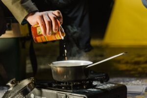 Photo of pouring soup into a pot colling outdoors on a camp stove