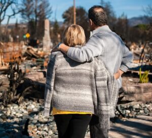 Man and his wife owners, checking burned and ruined house and yard after fire, consequences of fire disaster accident. Ruins after fire disaster.